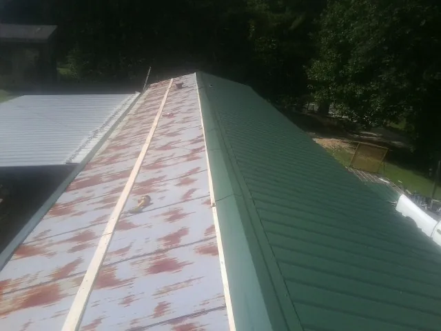 Old rusted panels beside newly installed green metal roofing — Wind Damage Roof Repair by Roofing Brothers in Cape Canaveral