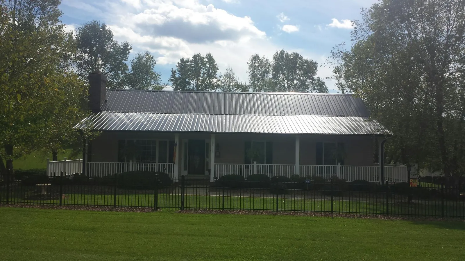 Gray metal roof on a brick ranch with a full width front porch — Gutter Guard Installation work by our crew in Cape Canaveral