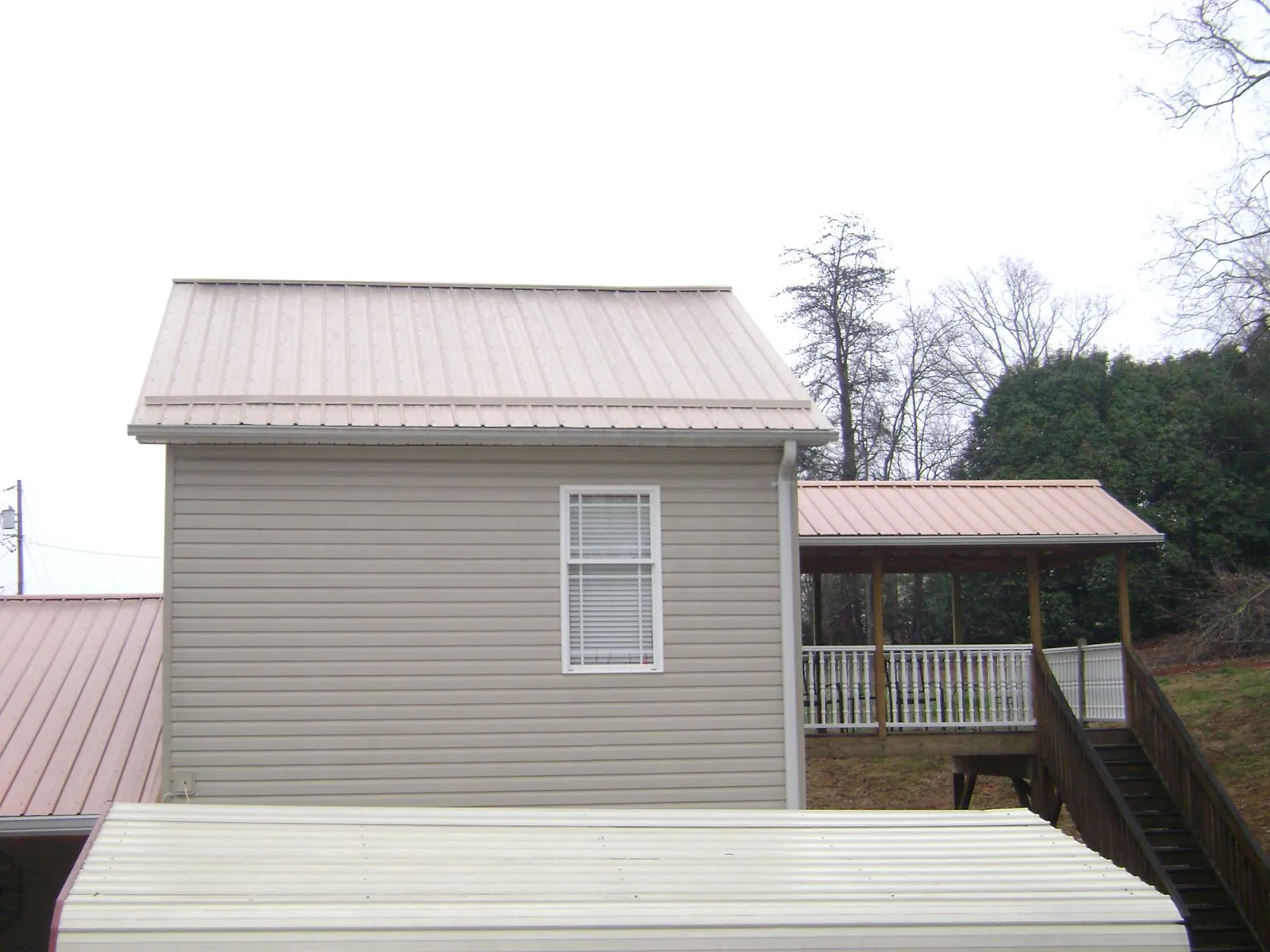 Tan metal roofs on a two story addition and attached porch, from a Roof Replacement job in Cape Canaveral